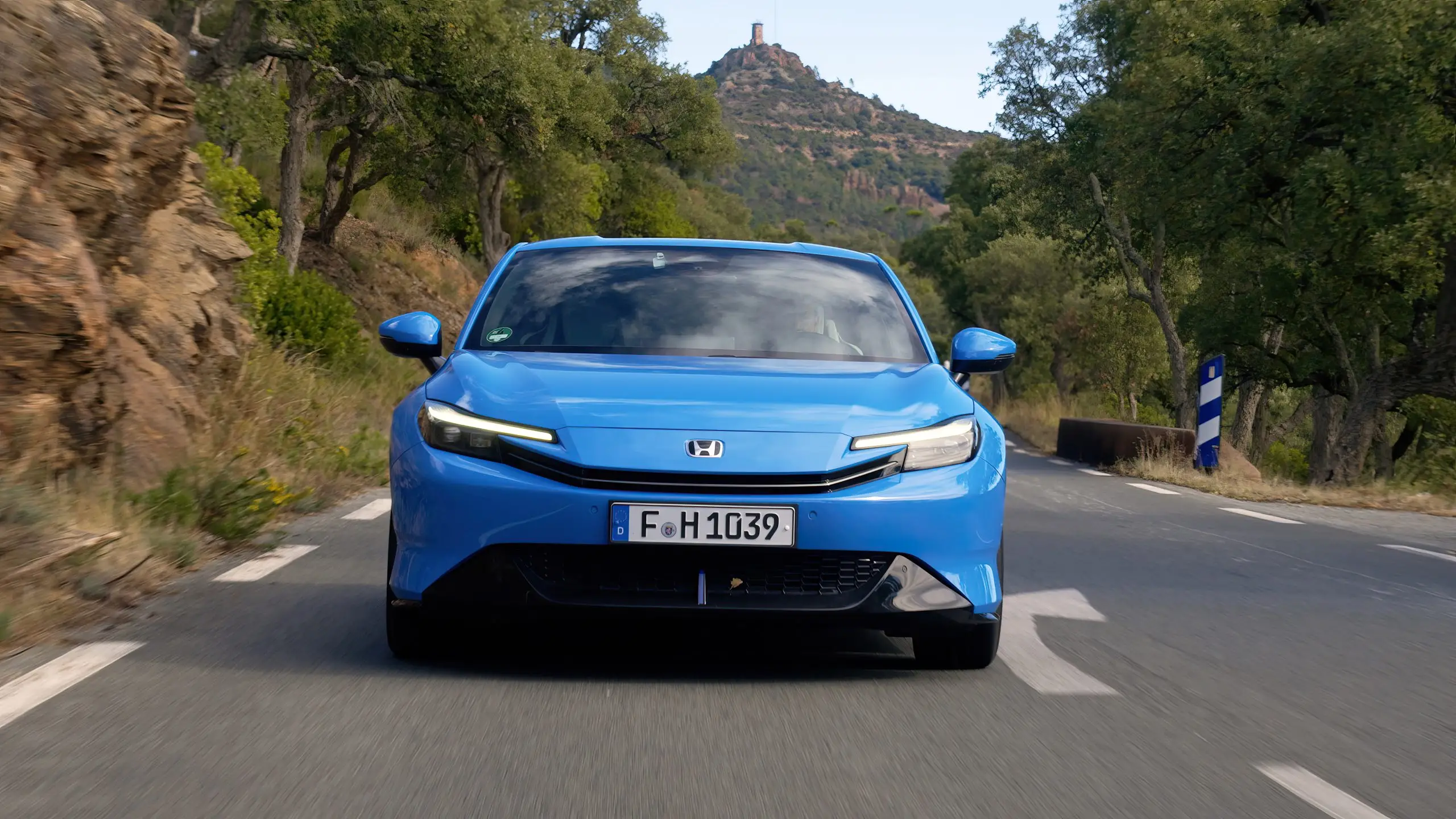 Blauer Honda Prelude fährt auf schmaler Bergstrasse durch bewaldete Kurven.
