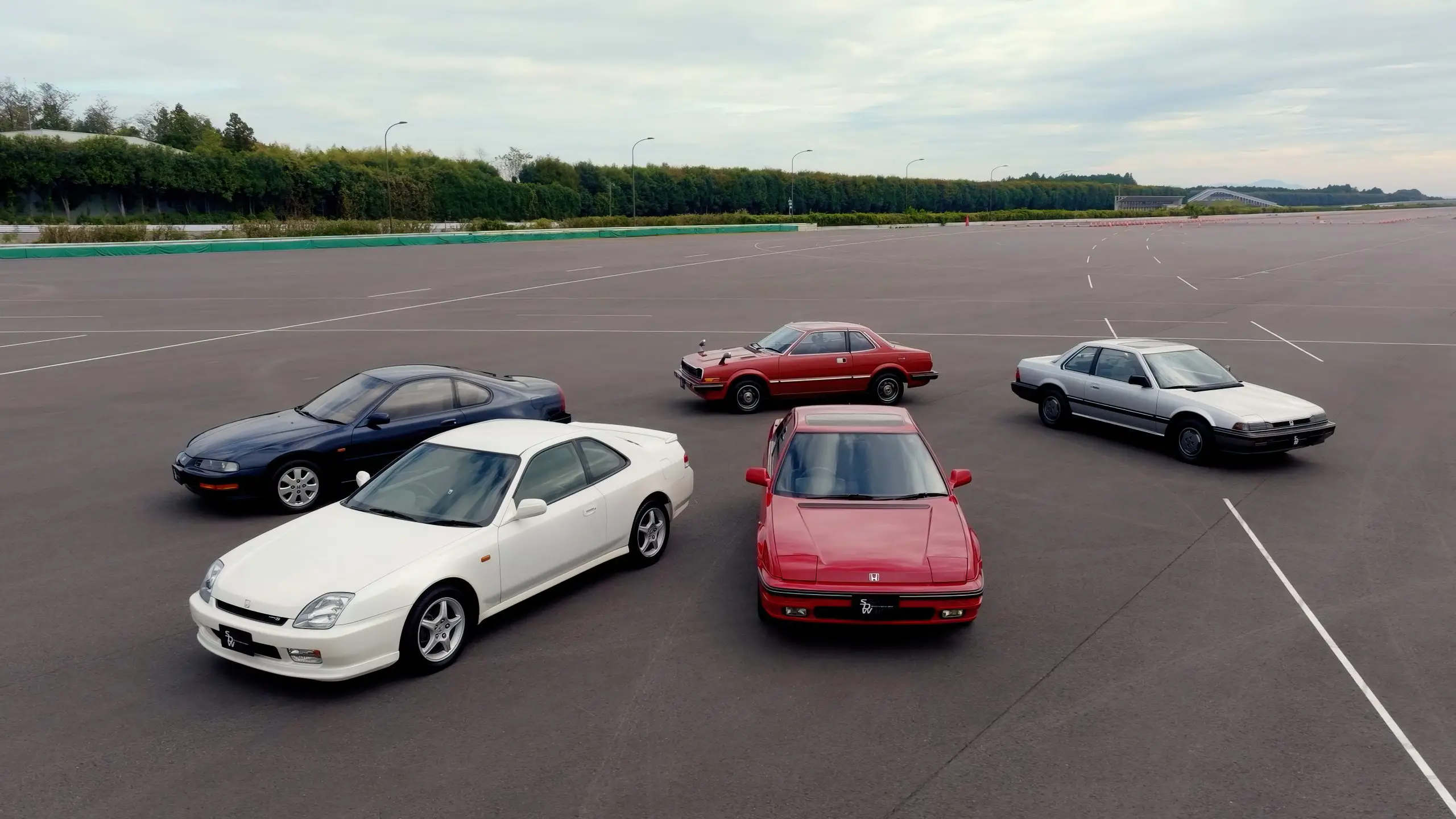 Fünf Honda Prelude-Generationen stehen auf einem leeren Testgelände nebeneinander.