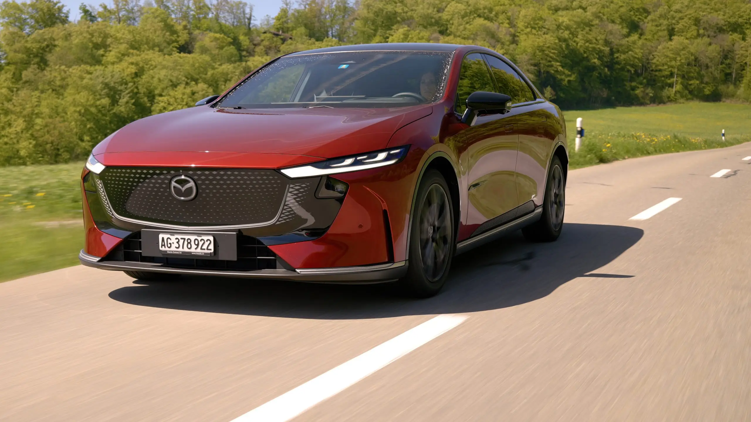 Roter Mazda 6e fährt auf einer Landstrasse, aufgenommen schräg von vorn.