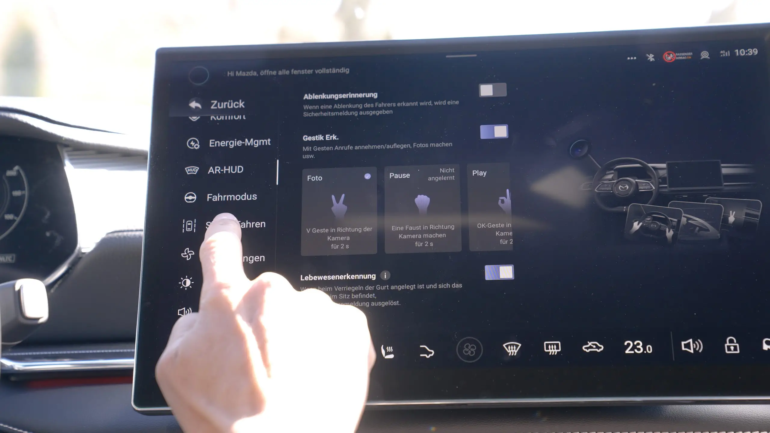 Hand tippt auf den zentralen Touchscreen des Mazda 6e mit verschachtelten Einstellungsmenüs.