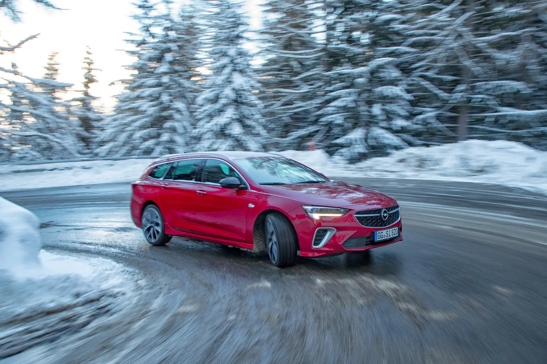Roter Opel Insignia GSi Sports Tourer fährt auf verschneiter Strasse durch einen Winterwald