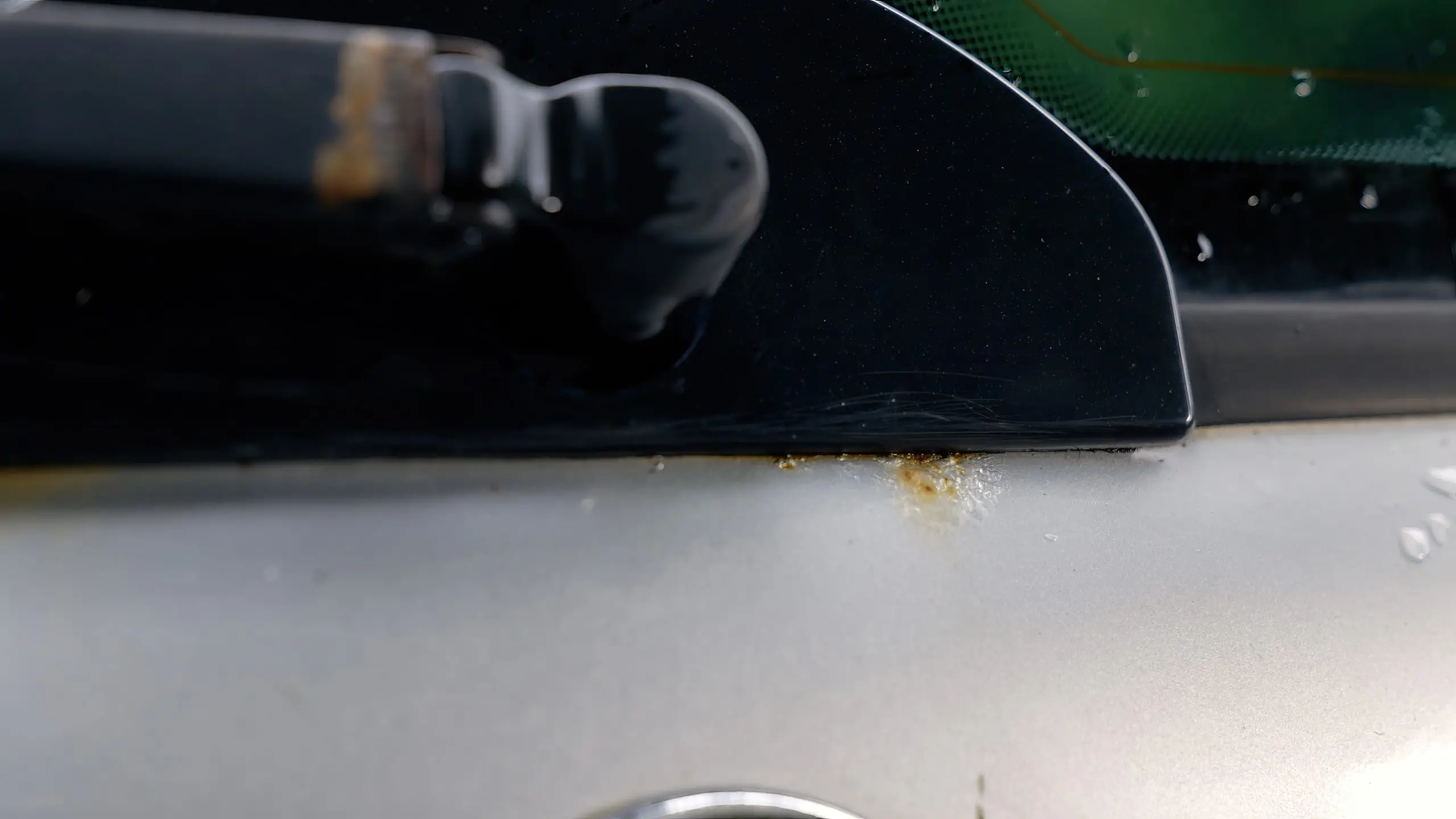 Rostflecken am unteren Rand der Heckscheibe eines silbernen Autos.