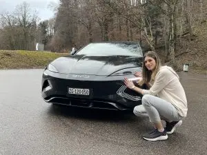 Schwarzer BYD Seal von vorne auf nasser Strasse, daneben kniet die Testerin.