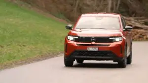 Roter Opel Frontera fährt frontal auf einer Landstrasse mit eingeschalteten LED-Scheinwerfern.