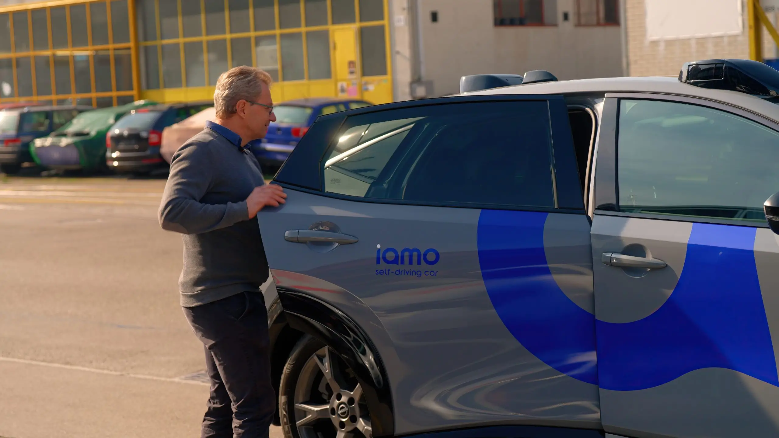 Raphael Murri steht neben dem iamo-Testfahrzeug auf einem Parkplatz in Regensdorf.