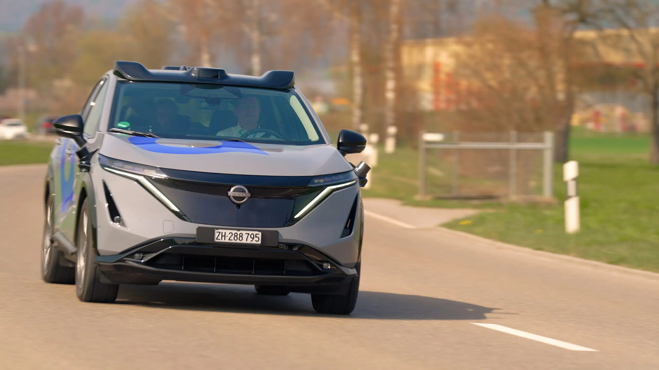 Selbstfahrendes Testauto mit Sensoraufbau fährt auf einer Strasse im Furttal.