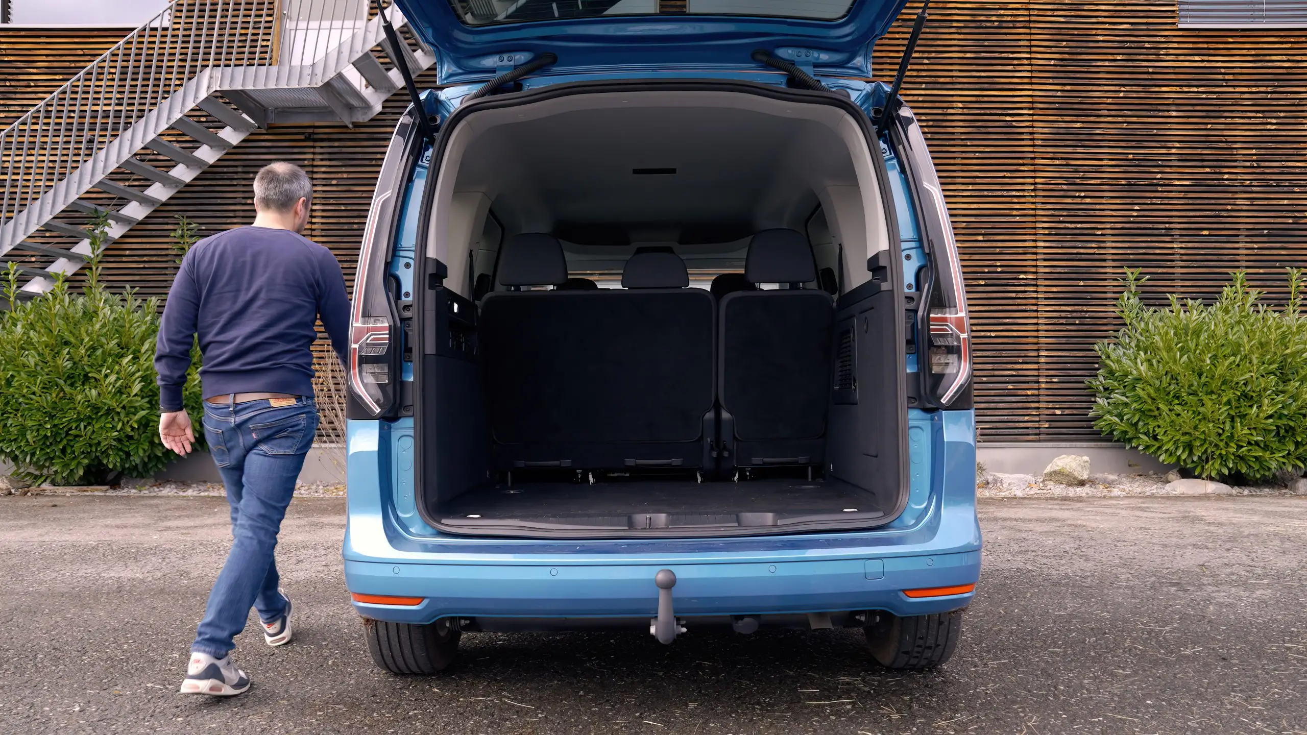 Geöffnete Heckklappe eines blauen VW Caddy mit grossem Laderaum hinter der zweiten Sitzreihe.
