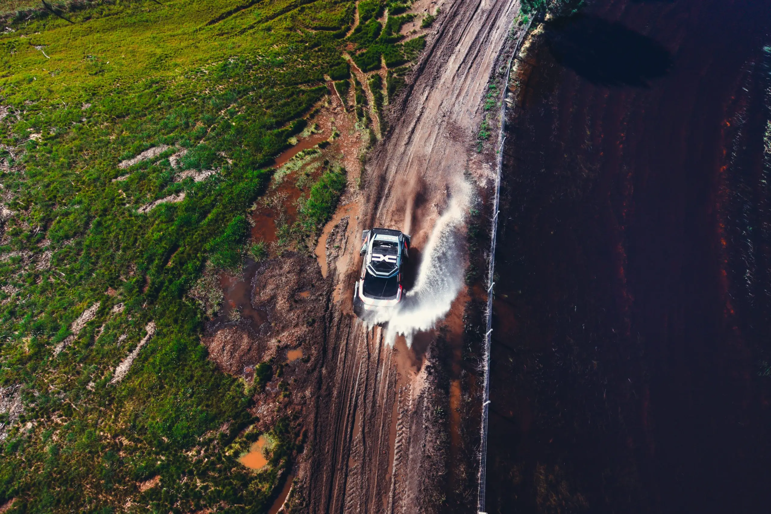 Der Dacia Sandrider durchfährt eine schlammige Wasserpassage auf einer Rally-Raid-Strecke.