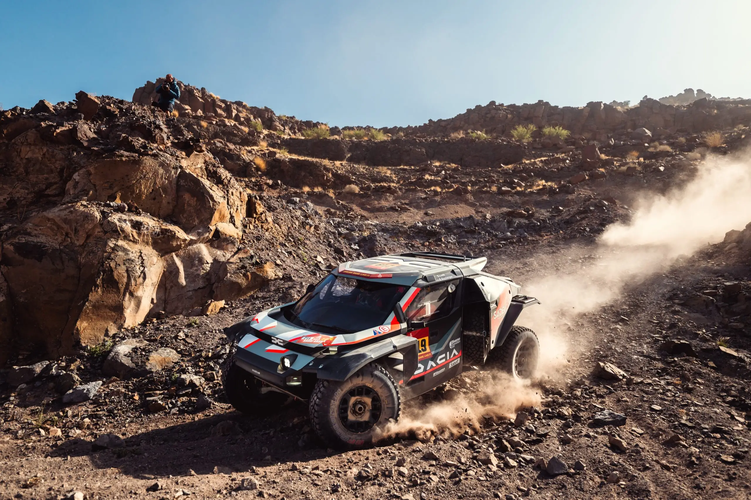 Der Dacia Sandrider fährt auf grossen Rennreifen über eine felsige Offroad-Piste.