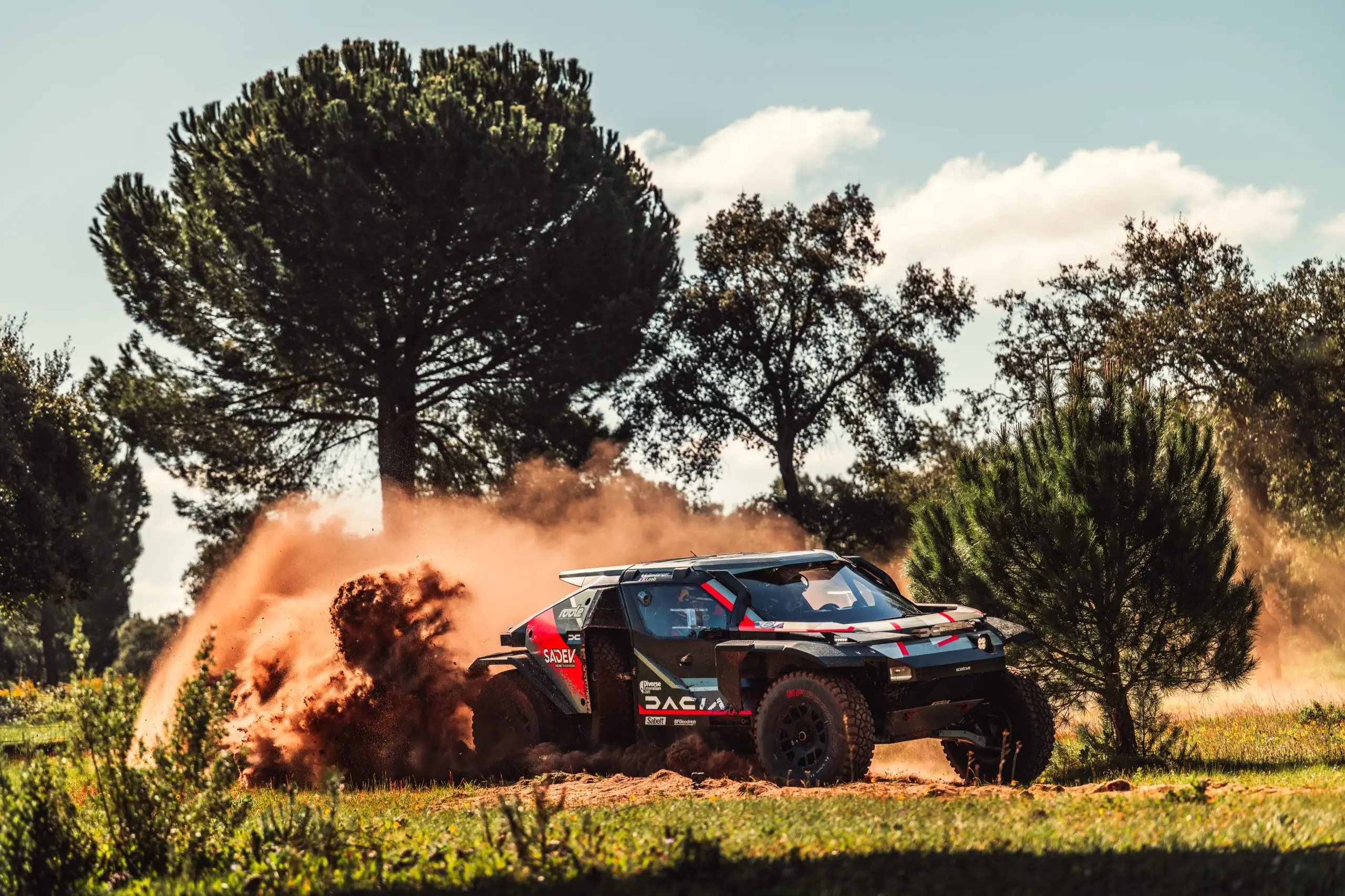 Der Dacia Sandrider rast über eine Schotterpiste und wirbelt hinter sich eine hohe Staubwolke auf.