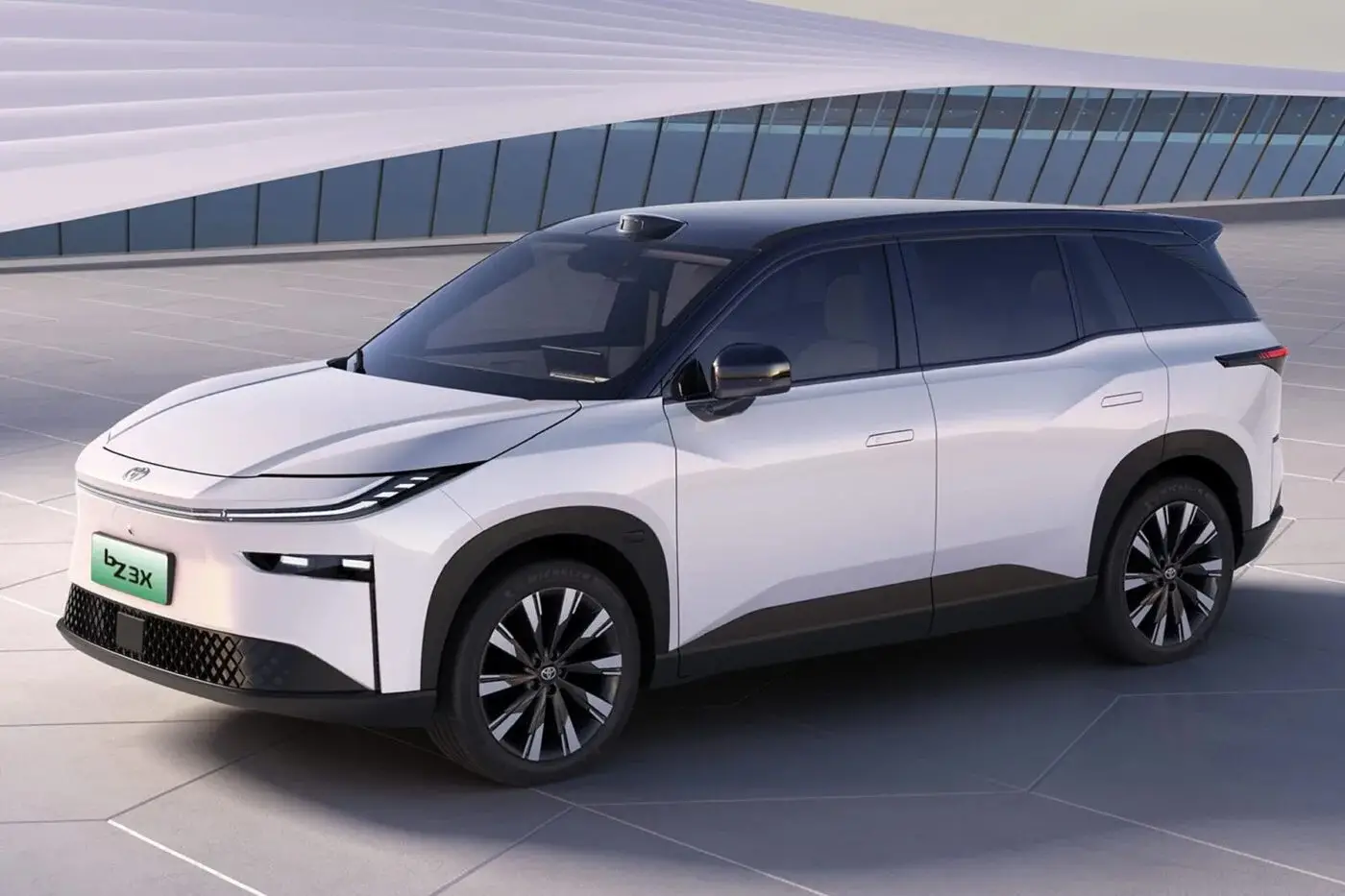 Weisser elektrischer Toyota bZ3X mit schwarzem Dach vor einem modernen Gebäude