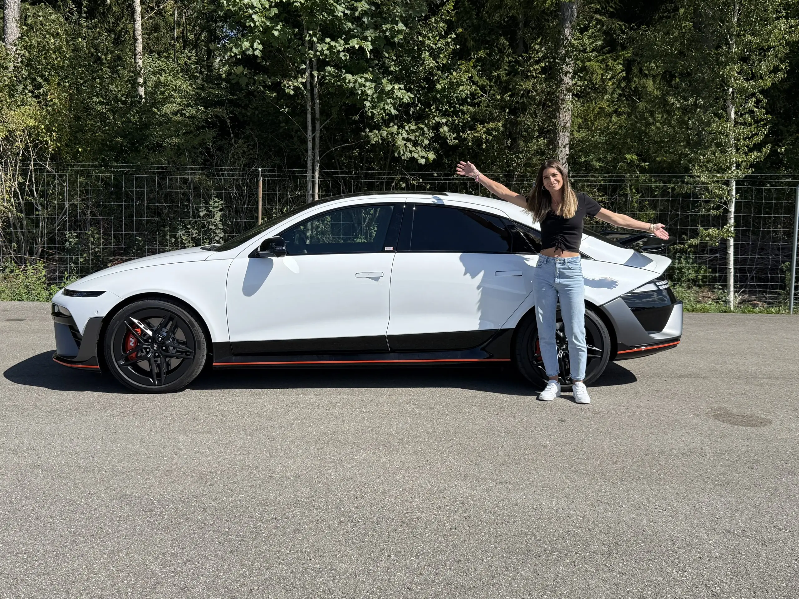 Cyndie steht neben einem weissen Hyundai Ioniq 6 N in Seitenansicht