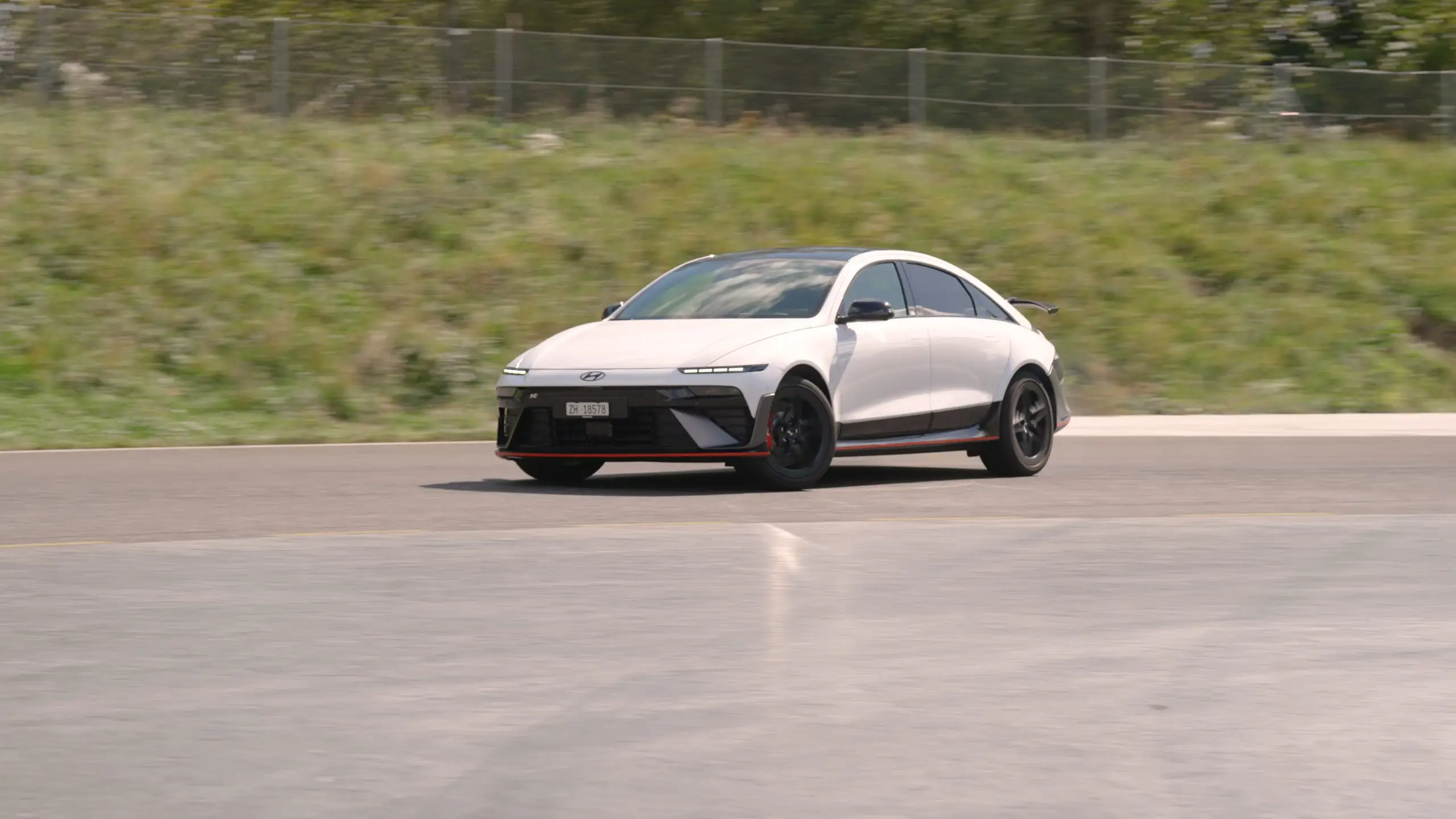 Weisser Ioniq 6 N fährt schnell durch eine Kurve auf einer Teststrecke