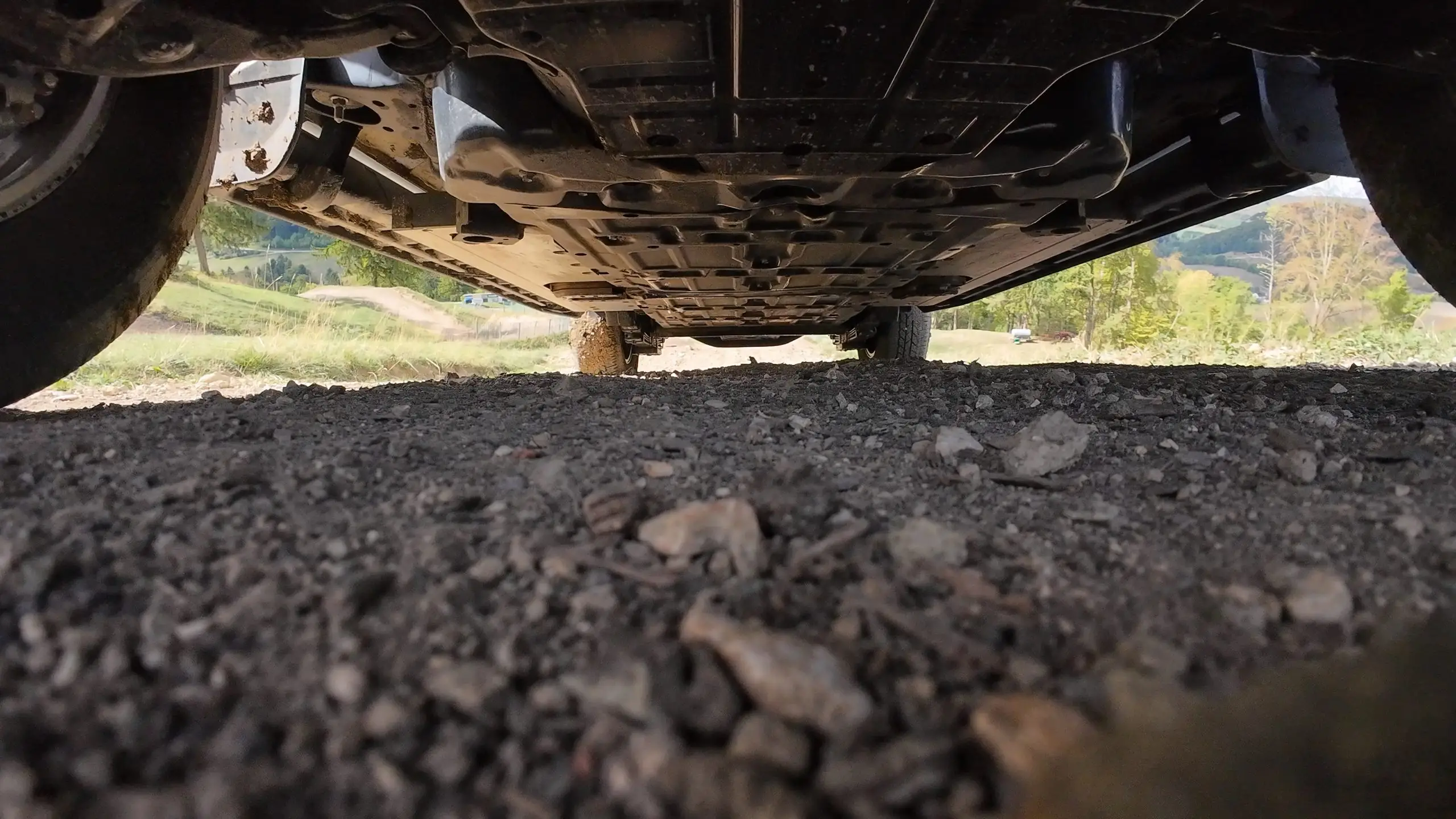 Unterboden des Toyota Hilux Elektro knapp über einer steinigen Geländekuppe.