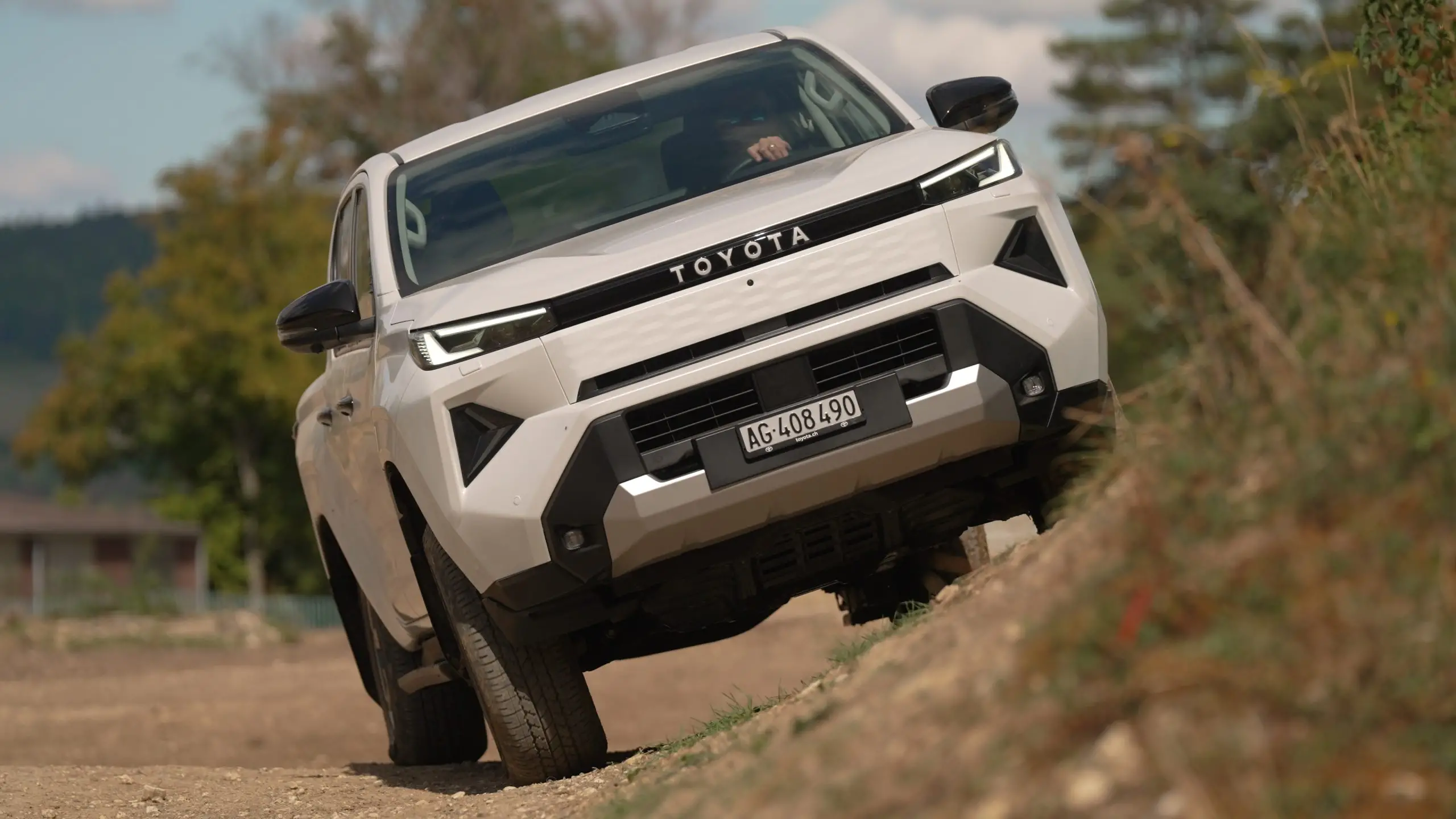 Toyota Hilux Elektro auf einer trockenen Offroad-Strecke in hügeligem Gelände.